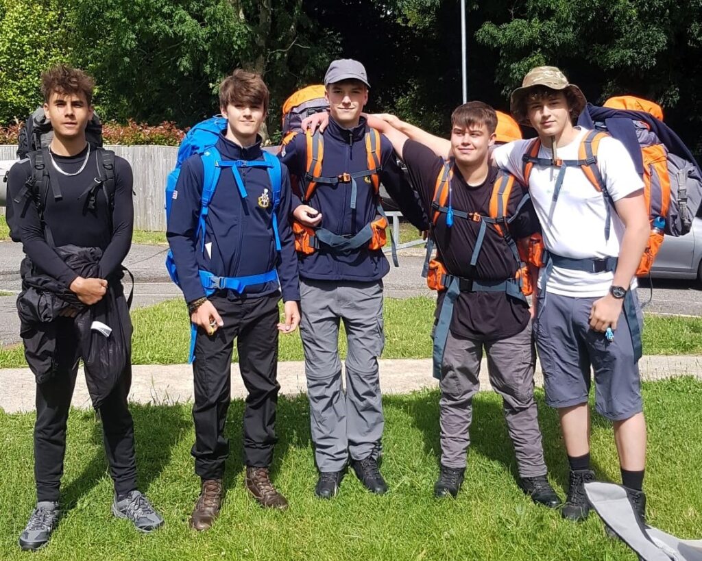 5 students posing for a photograph by the roadside