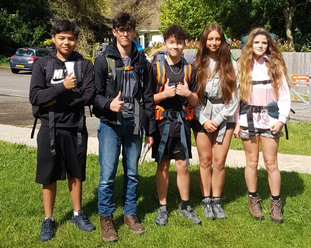 5 students posing for a photograph by the roadside