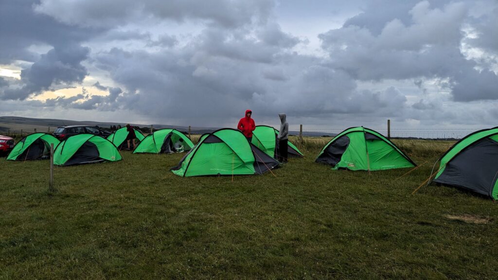 Wide shot of a dozen student tents set up while a pair are talking.