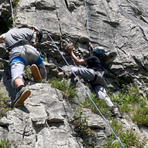 Two students climbing up cliff utilising harnesses at the CCF 2024 Training Camp.