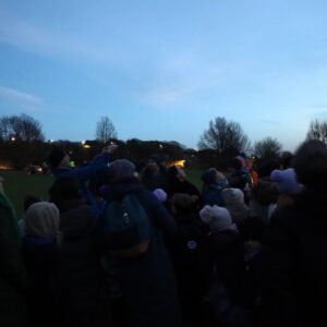 Photograph of crowd looking up at the skies looking at the stars.