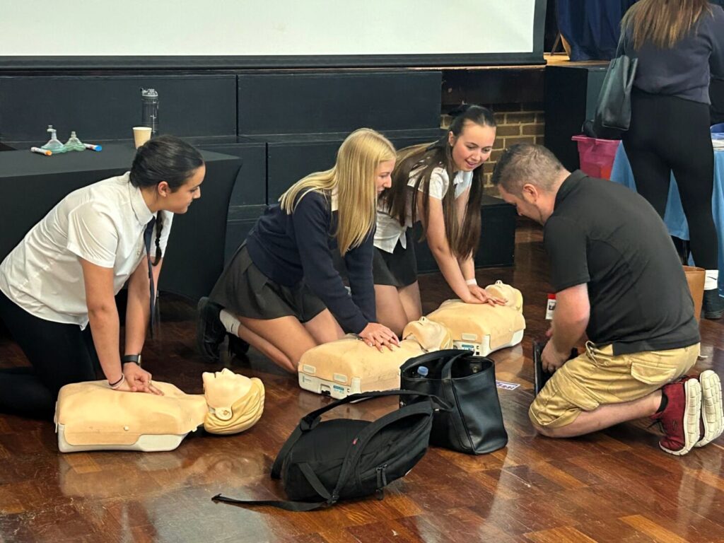 Students at Longhill's Career's Fair 2025, performing CPR on dummies in the Main School Hall.
