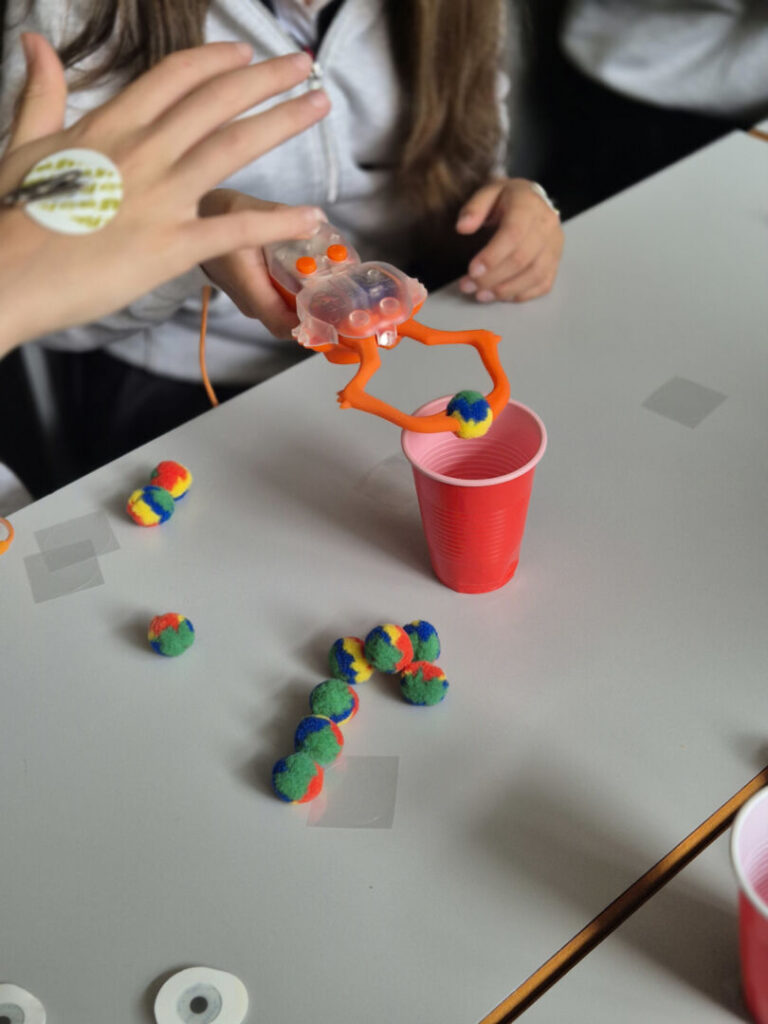 Students using the robotic arm pick up objects.