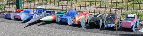 Race cars set up against the cage of the tennis court
