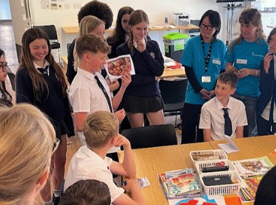 Students at the University of Brighton, participating in a exercise around a table.