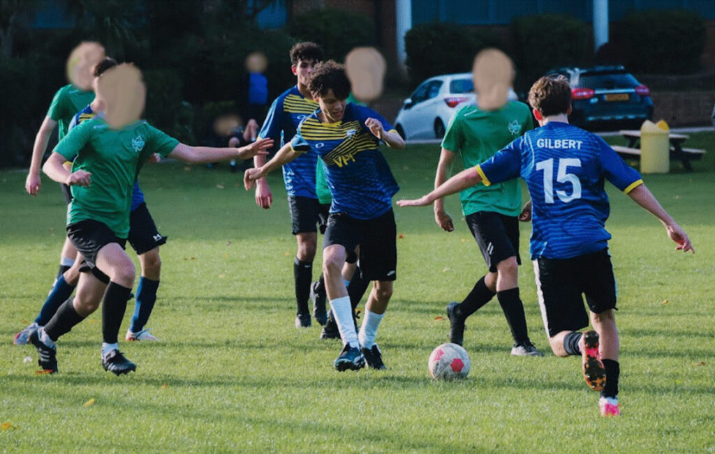 Students combining to get through heavy defensive pressure on football pitch.