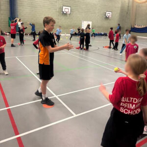 Longhill Sports leaders, demonstrating catching techniques to primary school students in the Sports hall.
