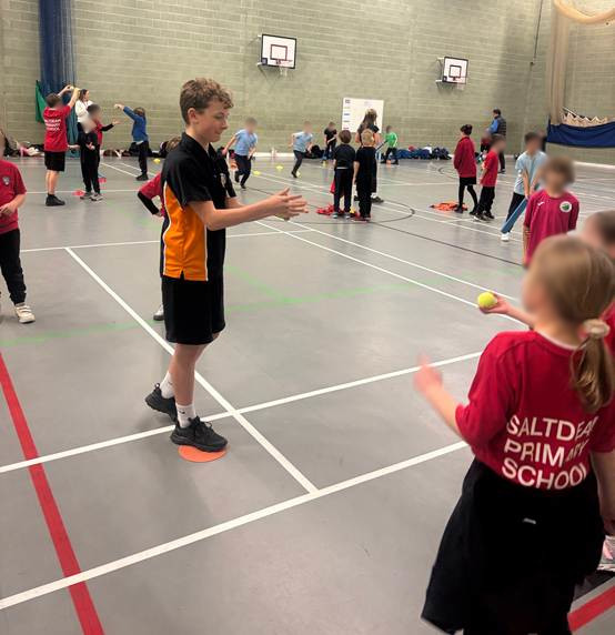 Longhill Sports leaders, demonstrating catching techniques to primary school students in the Sports hall.