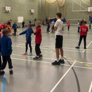 Wide shot of the sports hall while sports leaders are assisting with the Cricket Festival