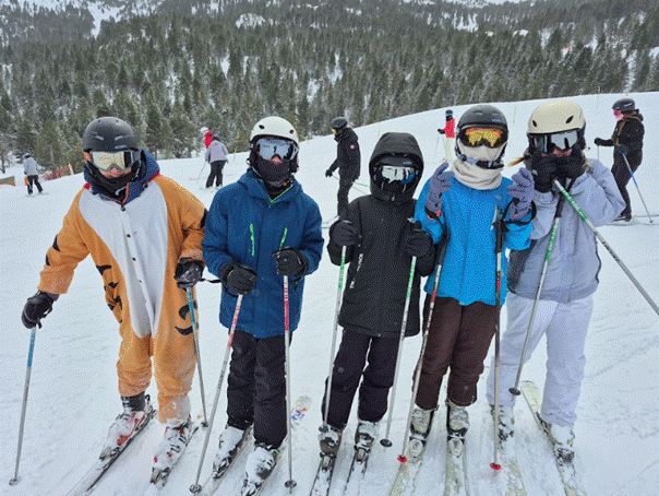 Students posing for photograph on top of a slope
