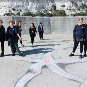 Students posing for photograph beside their artwork