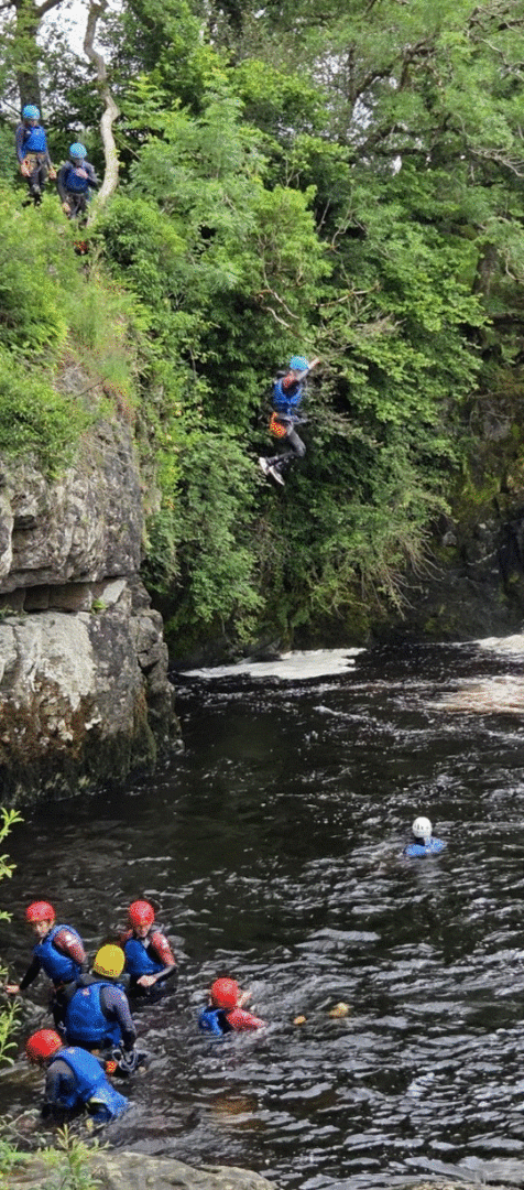 Cadets diving down from the rocks into the river.