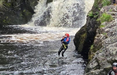 Cadet standing in the river by the waterfall